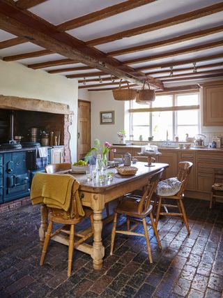 Wooden farmhouse kitchen with blue aga and wooden table and chairs in the centre