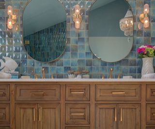 A bathroom with a wooden double vanity and blue wall tiles