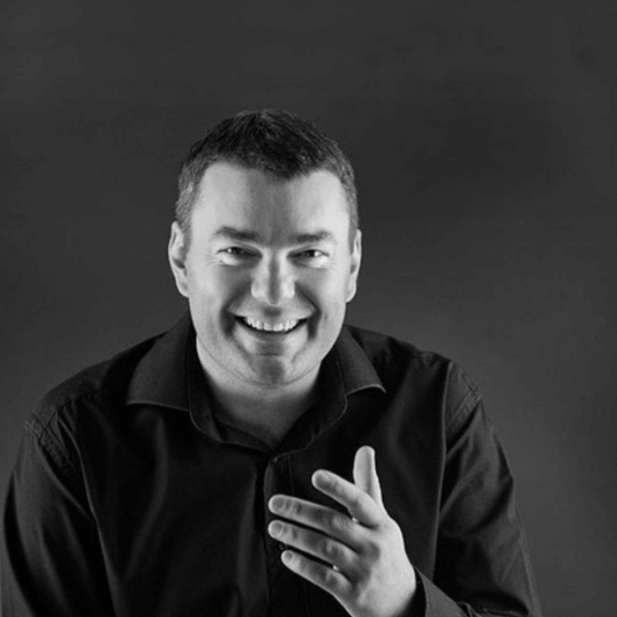 A black and white picture of Ivo Iv, a man wearing a black shirt against a black background