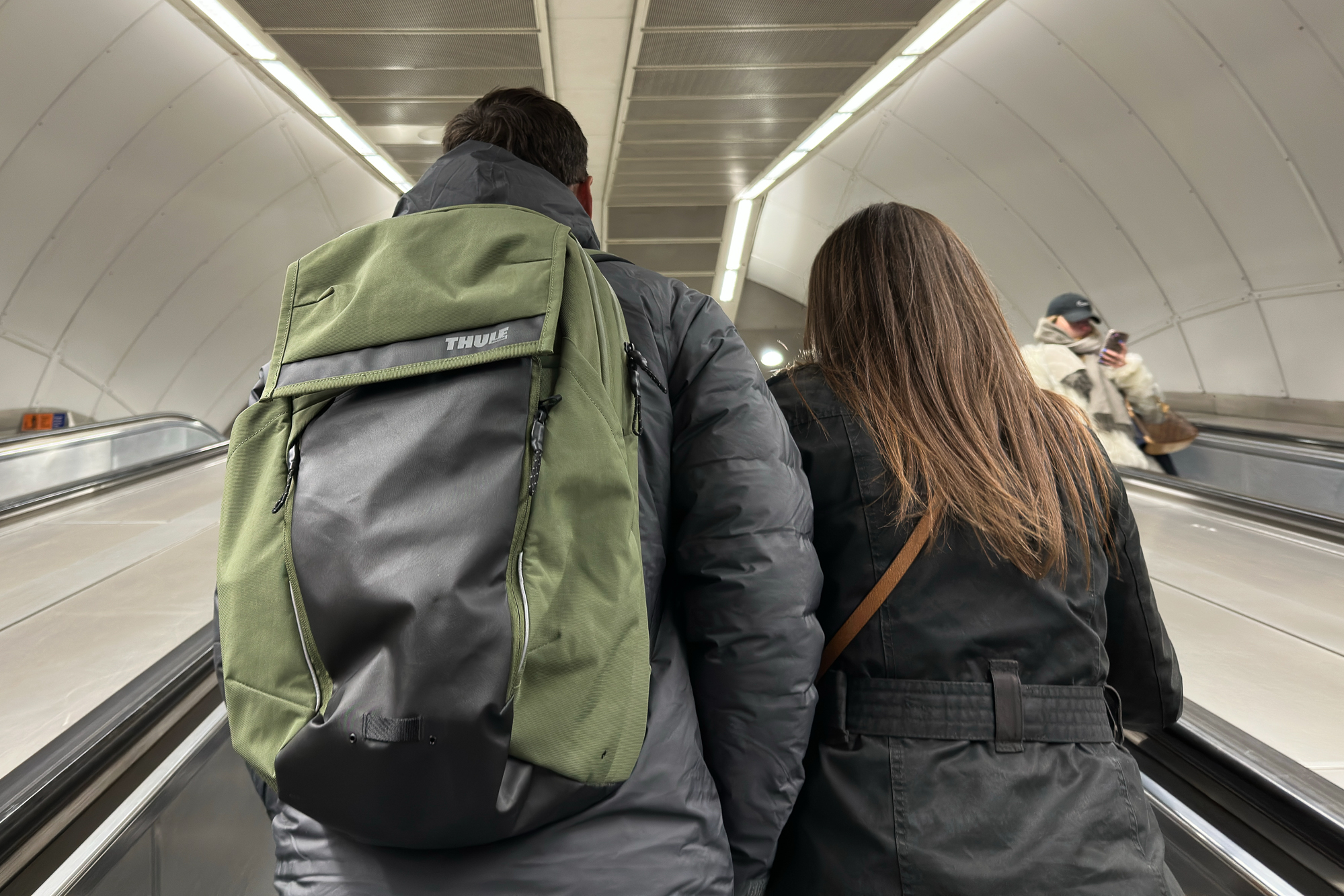 Man wearing a green Thule rucksack on an underground escalator