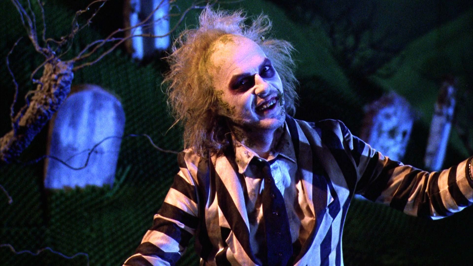 Michael Keaton's Beetlejuice smiles at the camera from a funny angle in his self-titled film