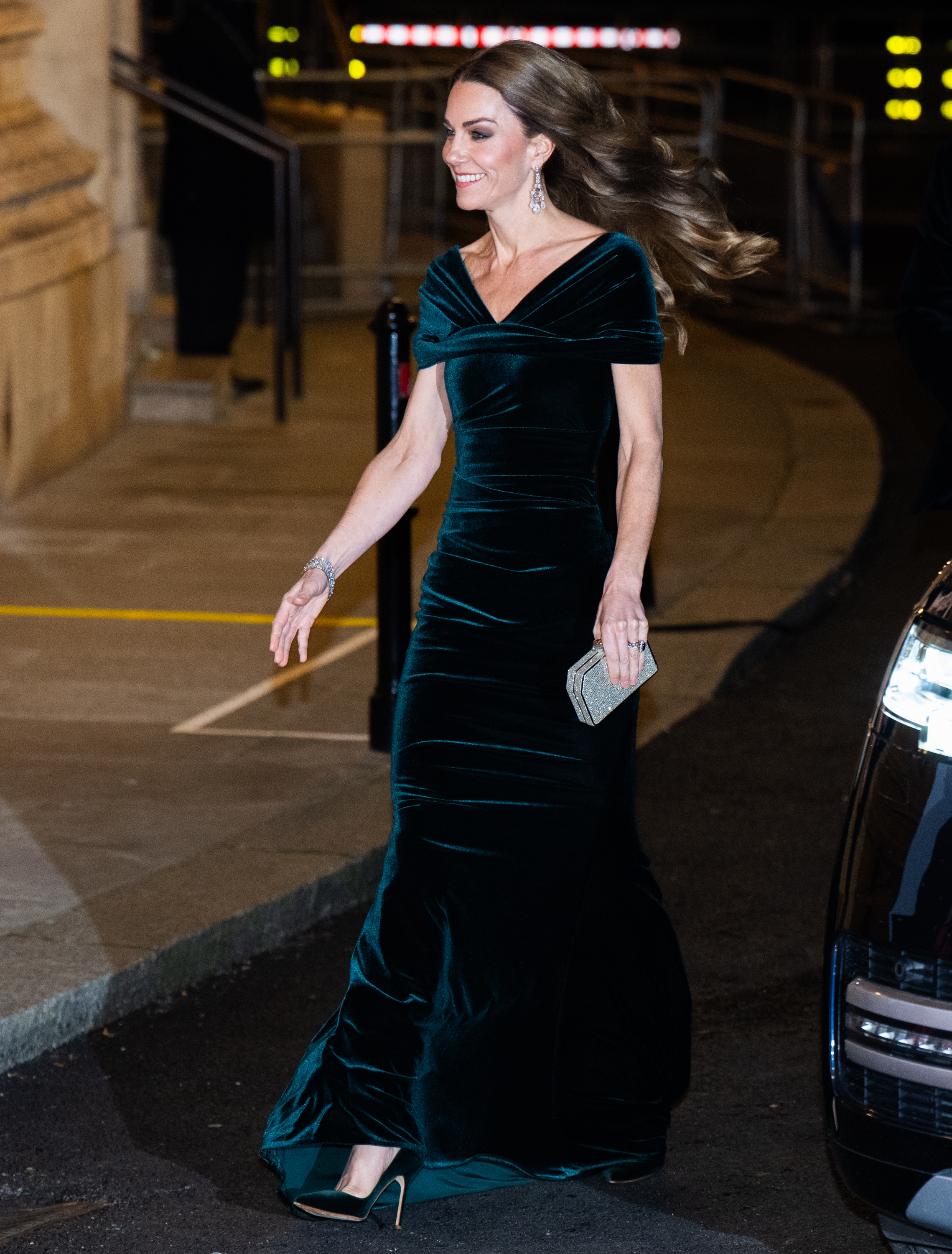 Kate Middleton wearing a green velvet gown walking with her arm out