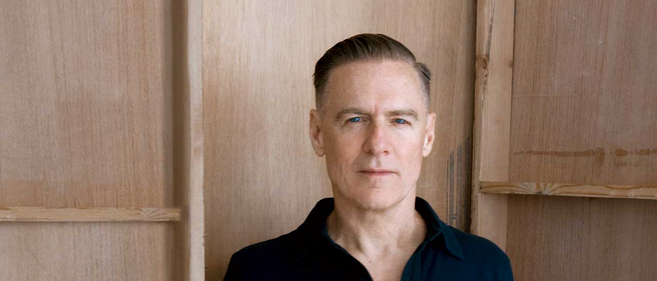 Bryan Adams pictured against a wooden background