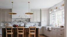 a neutral kitchen with a wood island and marble backsplash