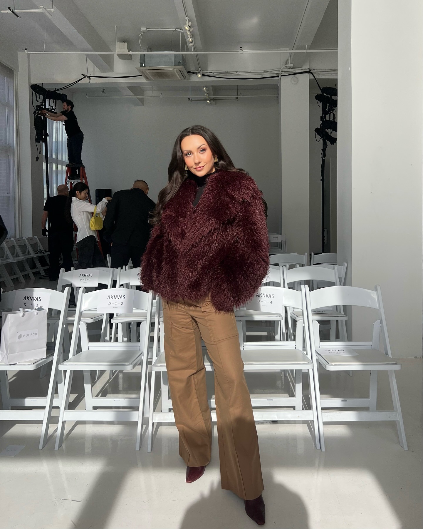 kendall wears burgundy fur coat, and flared tan trousers with pointed toe heels