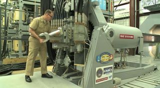 A video screenshot shows the Navy's new railgun prototype being loaded for firing tests.