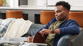 Man sitting on couch wearing Fitbit Charge 5