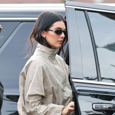 Kendall Jenner wearing a funnel-neck jacket and capri pants with high-heel thong sandals at the Super Bowl in 2026