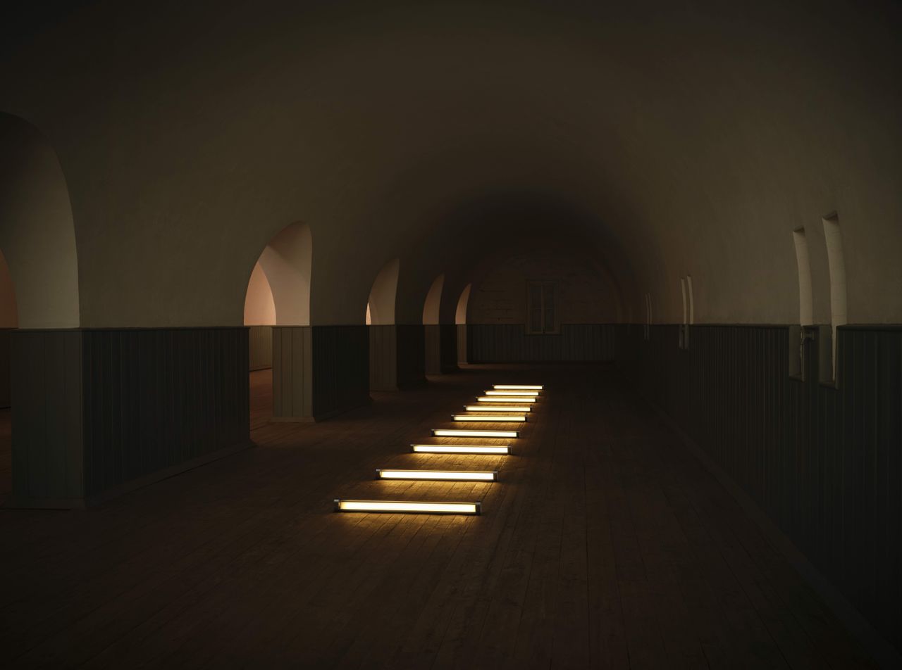 A dark-lit room with futuristic, sci-fi arches is brought to life by linear, neon-like lights.