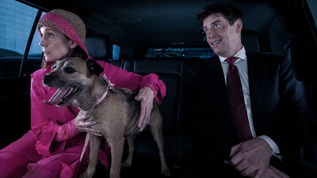 Pictured (L-R): Carrie Preston as Elsbeth Tascioni with her dog, she&#039;s looking out the window, and Christian Borle as Carter Schmidt sitting in a car together.