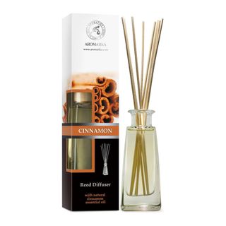 Glass reed diffuser bottle sitting next to the cinnamon-inspired packaging