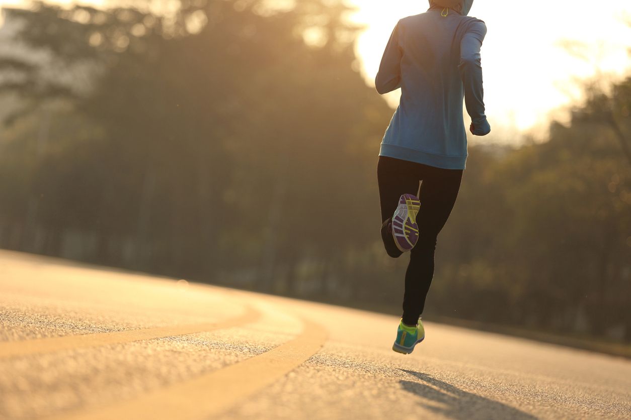 A woman runs down a road.