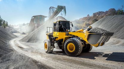 digger moving rock at construction site