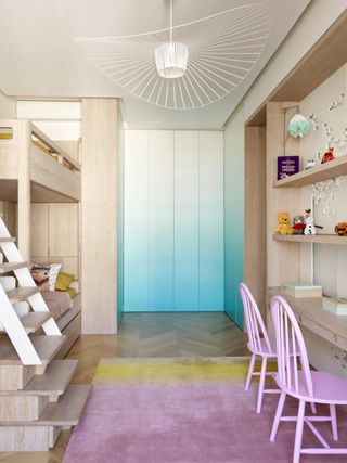 blonde wood children's twin bedroom with bunks, wall storage, turquoise ombre wardrobe walls, twin pink chairs, herringbone floor, pink and yellow rug