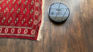 The Ultenic D5s Pro Robot Vacuum and Mop cleaning a hard floor next to a rug