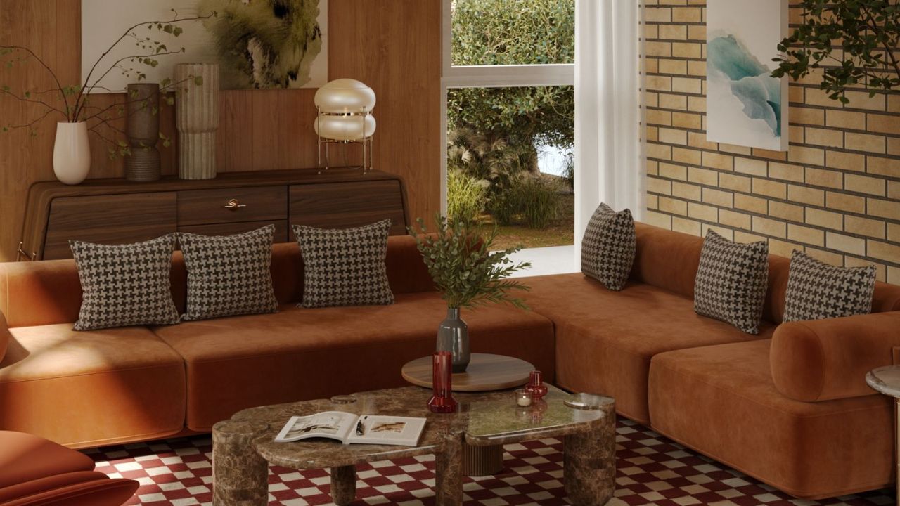 Brick and wood living room with warm orange, brown and white theme. There is a brown and white large area checkered rug and brown and cream checkered throw pillows on orange sofas, plus, mid century wooden sideboard, and a rounded marble table