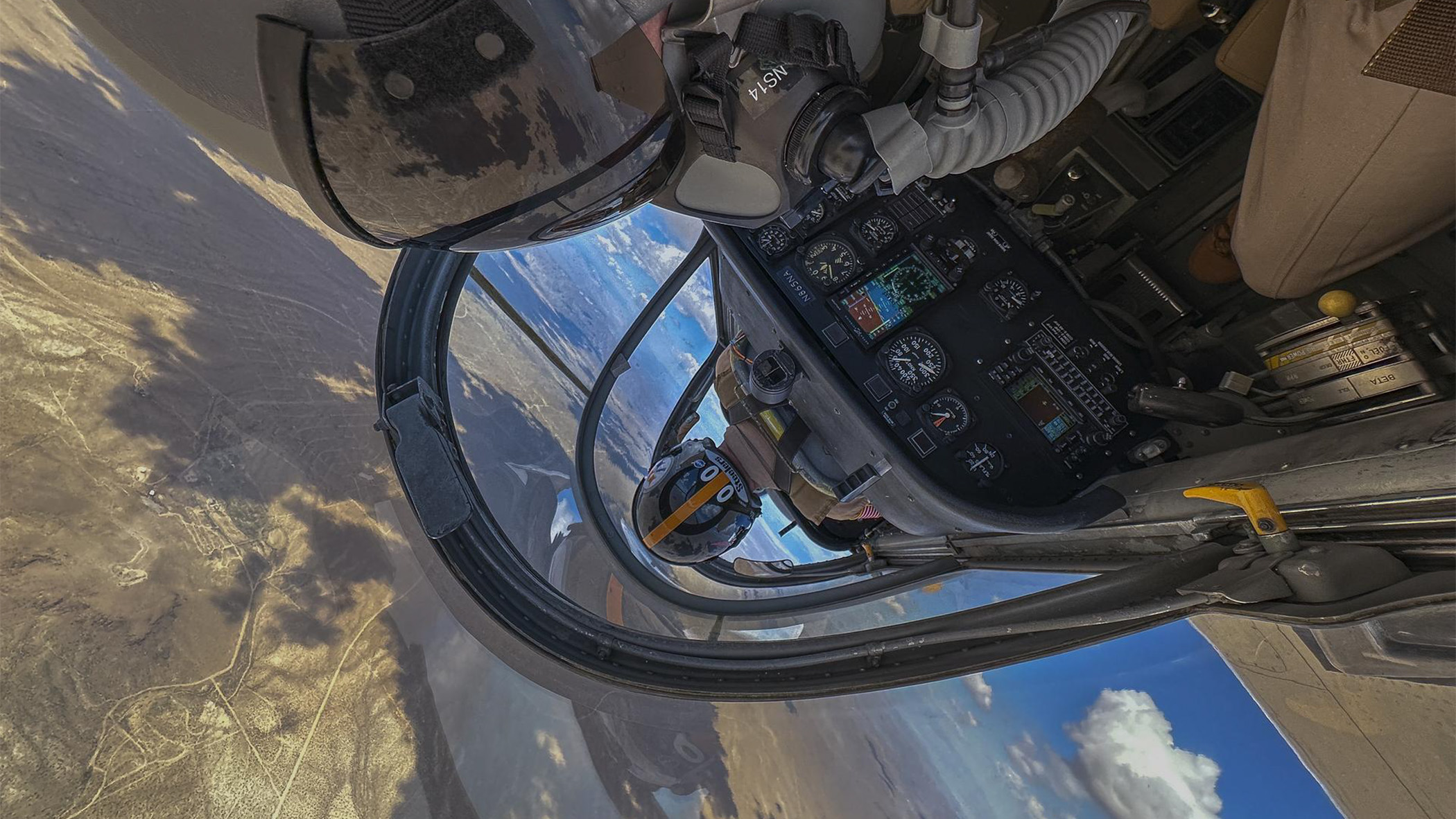 Photographer takes inverted aerial picture of pilot from backseat of fighter jet aircraft.