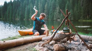 Man using camping axe to split wood for campfire
