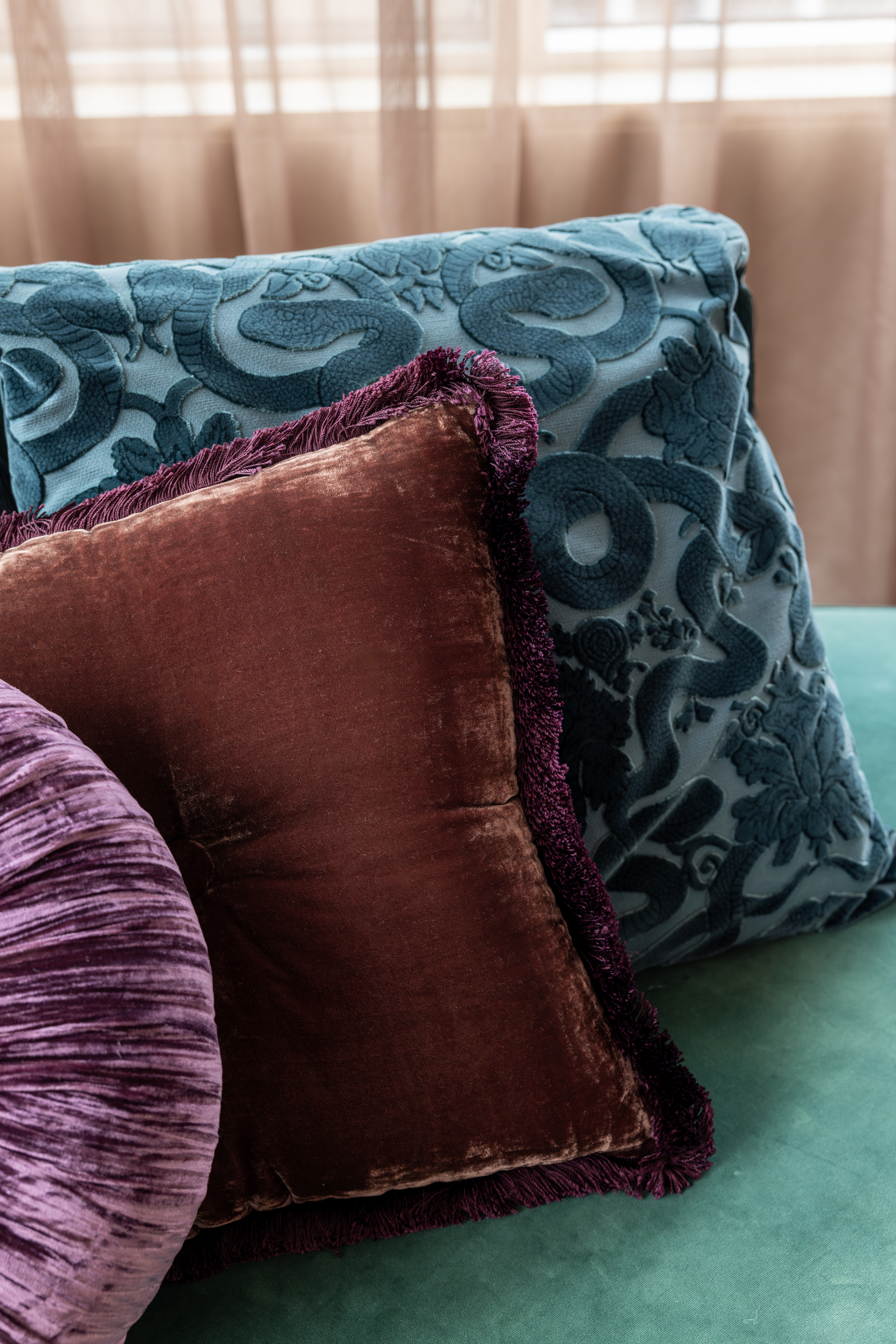 A close up of the multicolored pillows on the green sofa