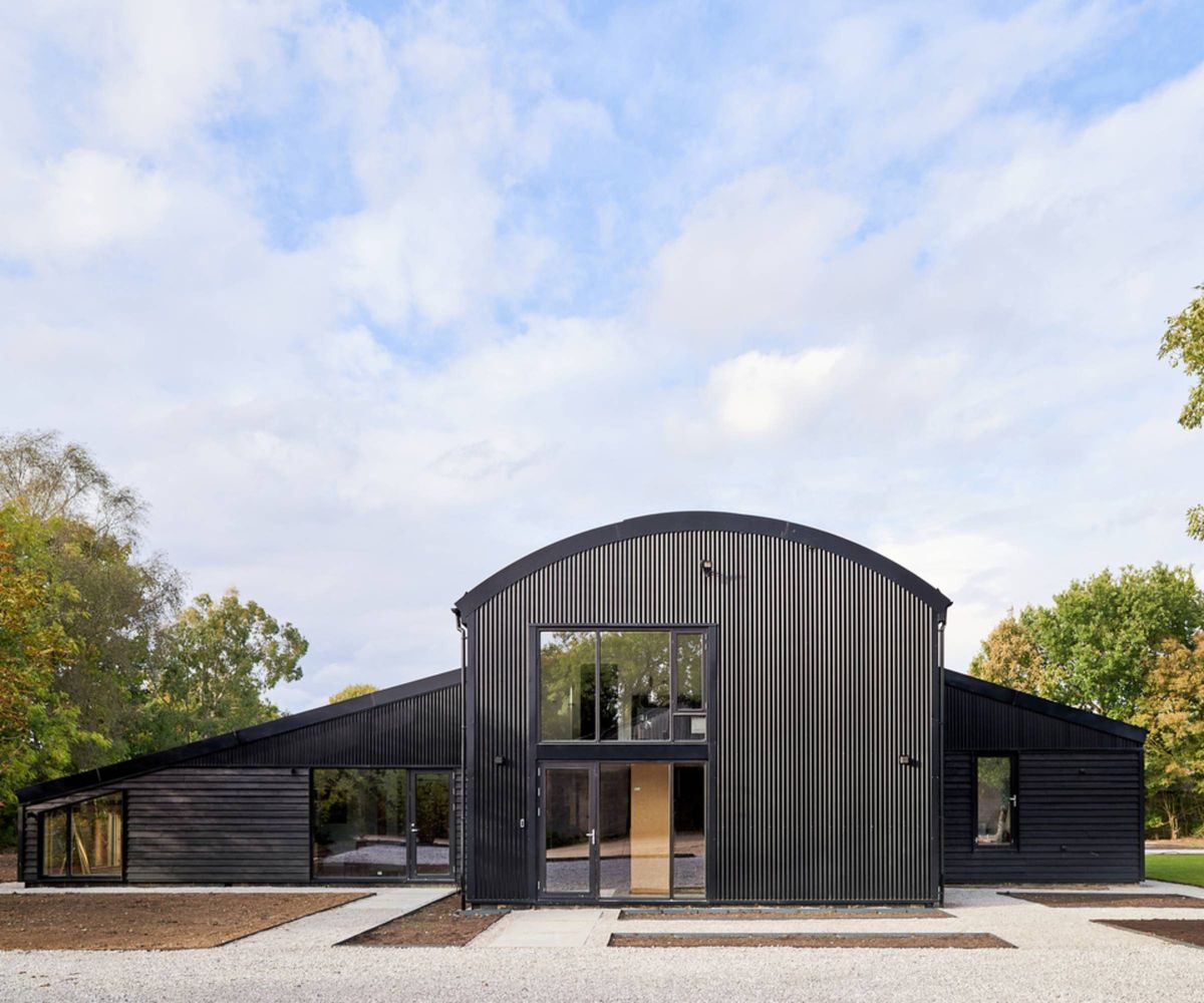 exterior of black dutch barn with central section with curved roof and two sections to side with sloping roofs