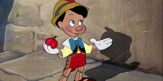 Pinocchio standing with an apple in hand
