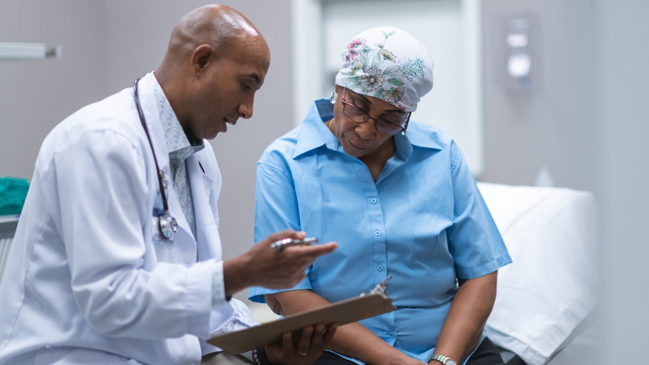 A senior woman at the doctor wearing a scarf on her head.