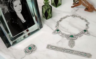 Platinum plaque clip brooch, bracelet and necklace, with emerald and diamond on table top