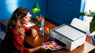 A woman takes a photo out of her HP Smart Tank printer in a colourful home