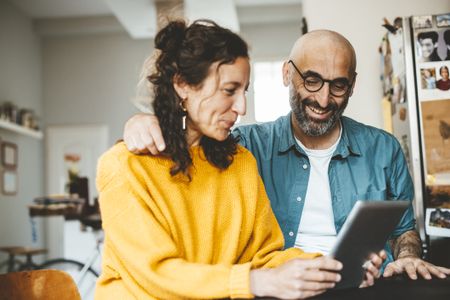 A middle-aged couple look at how much state pension they could get on a tablet computer (image: Getty Images)