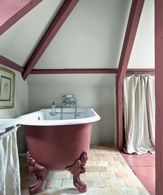 A small alcove bathroom with bath and wooden beams painted in Eating Room Red by Farrow & Ball