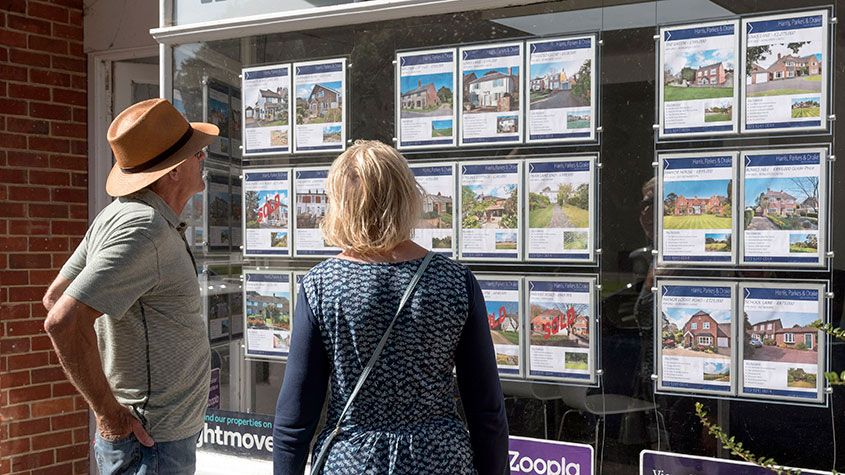 Couple looking in an estate agent&amp;#039;s window