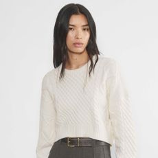 Aritzia model wearing cropped cableknit sweater.