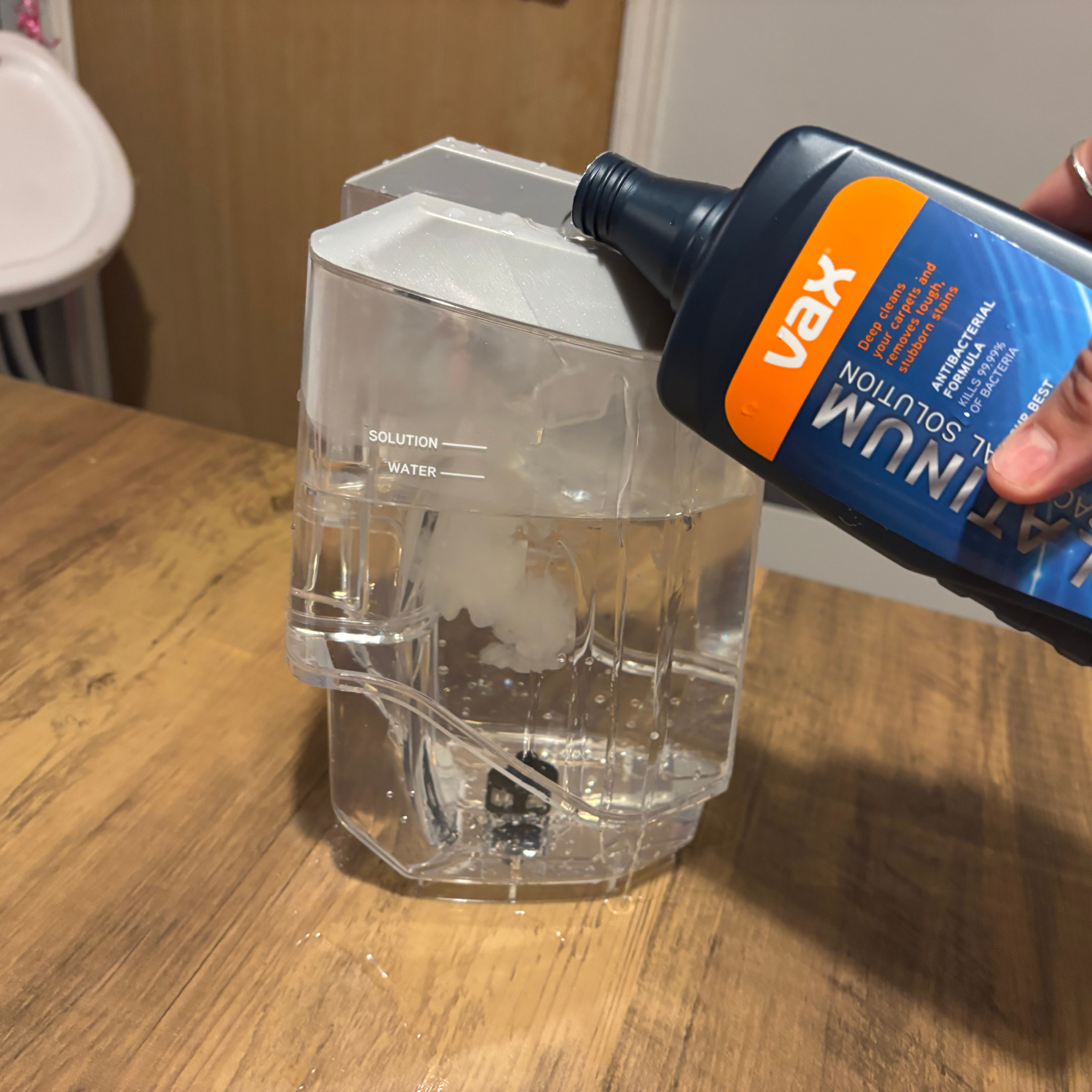 Bottle of the VAX antibacterial solution being poured into the clean water tank