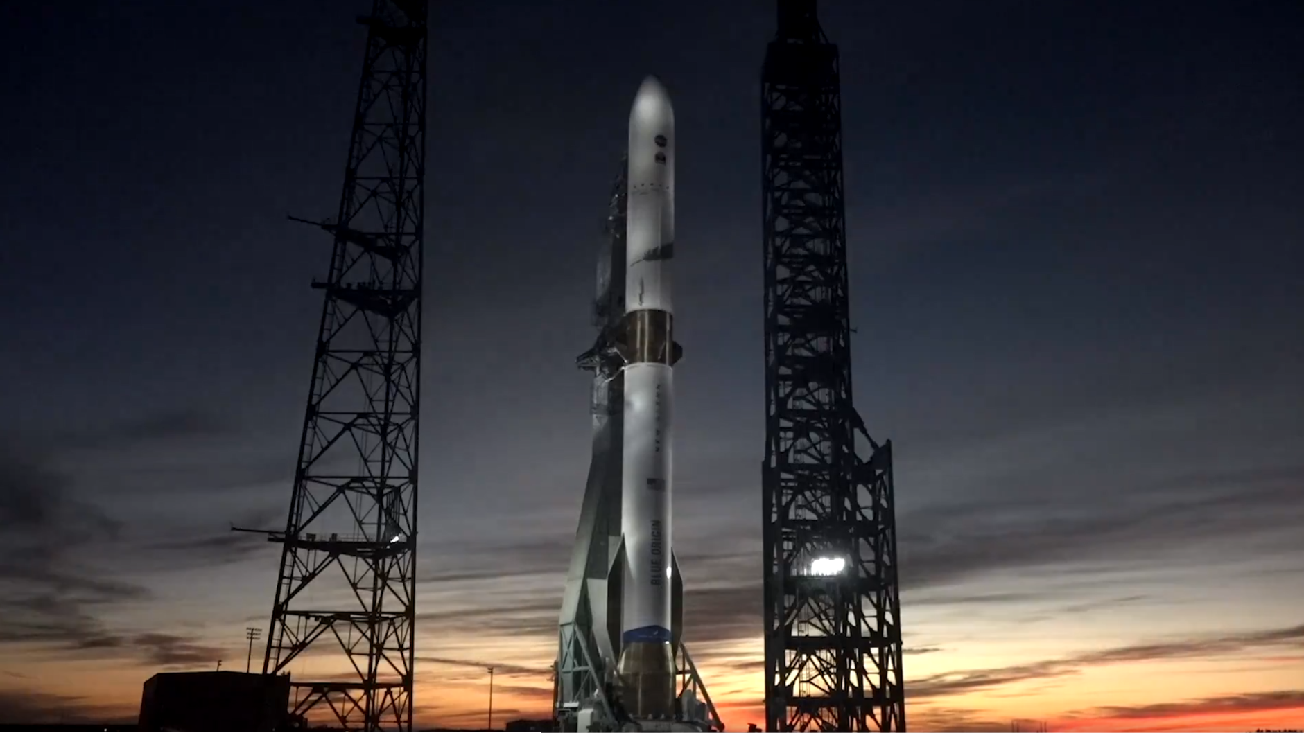 A white rocket stands against a setting sunet-painted sky.