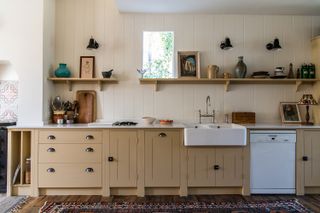 A yellow country kitchen with white walls and open wooden storage above