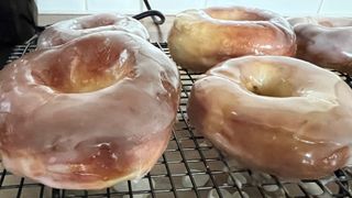 Donuts som tillagats i en airfryer och sedan glaserats ligger på ett ugnsgaller.