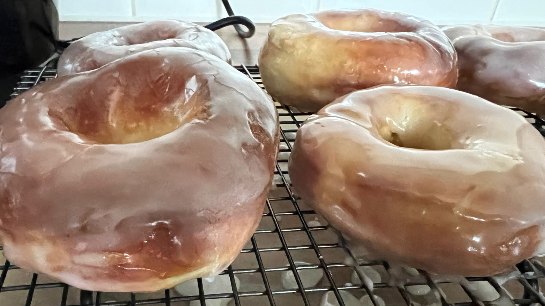 Donuts som tillagats i en airfryer och sedan glaserats ligger på ett ugnsgaller.