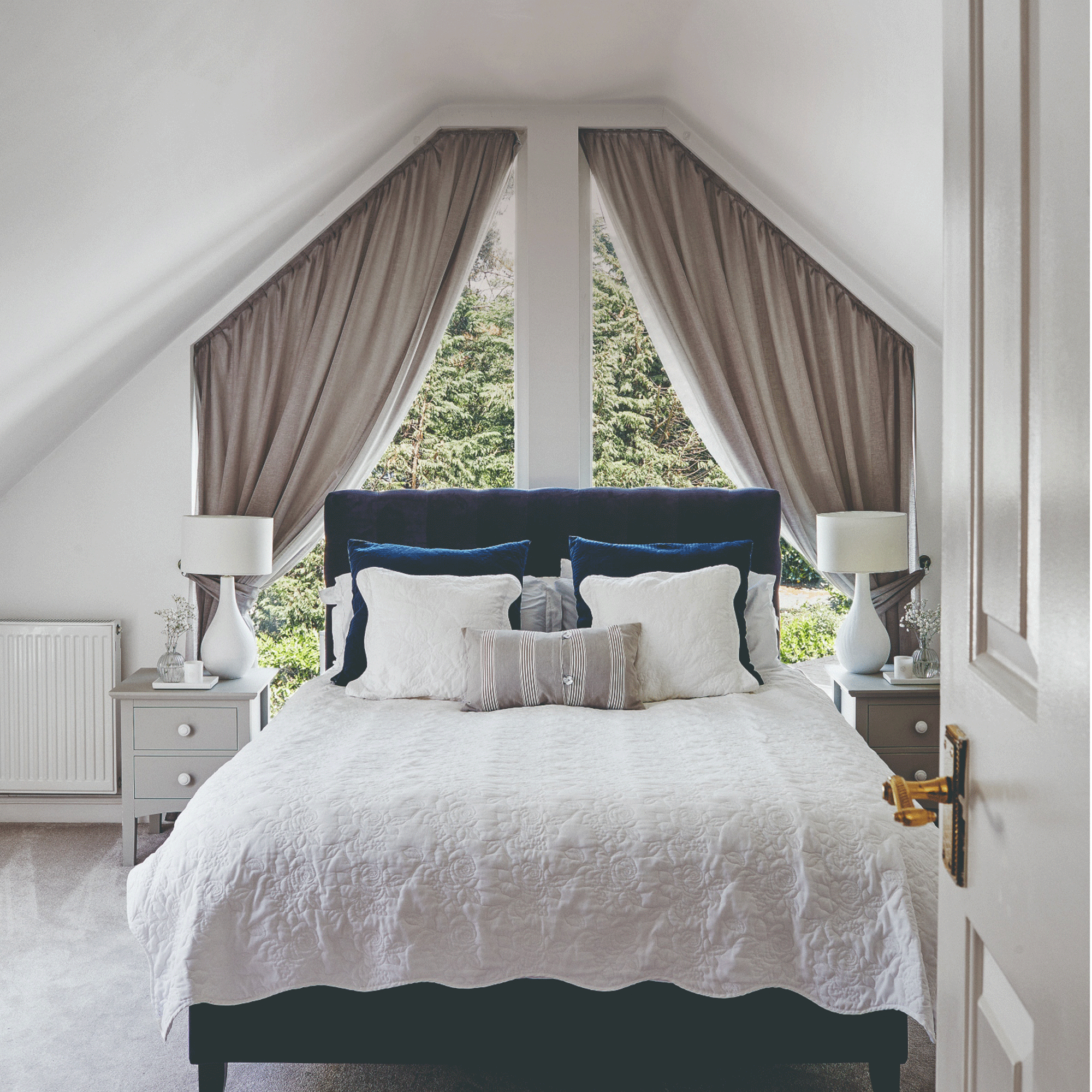 White bedroom with grey curtains and bed