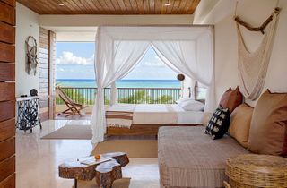 A bedroom with a four poster bed and natural elements dotting the walls