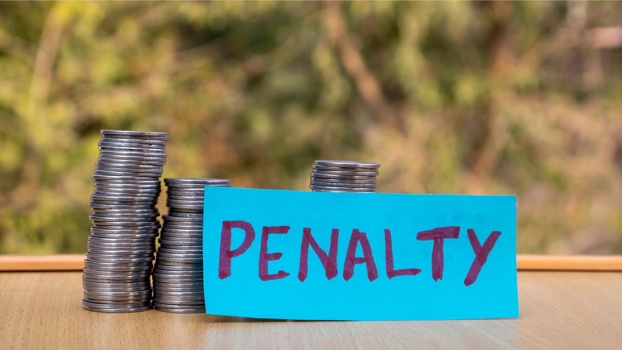 A blue sign with the word penalty written in purple sits in front of several stacks of coins.