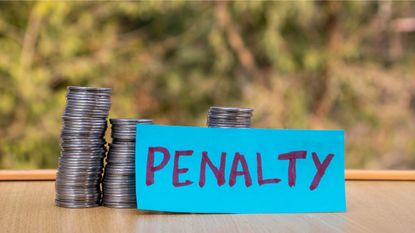 A blue sign with the word penalty written in purple sits in front of several stacks of coins.