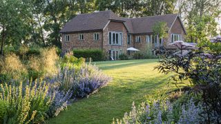 large lawned garden with established plants and brick self build