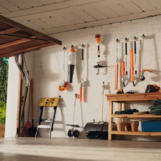 Interior of a white painted garage with STIHL garden tools hung in a line on the wall