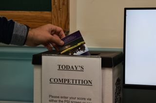 Golfer putting scorecard into competition box