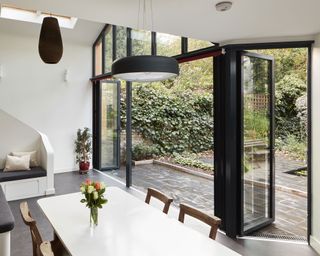 An example of installing patio doors showing a kitchen extension with a white dining table next to black bifold doors