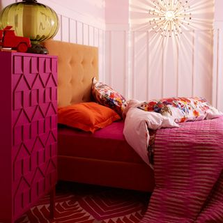 bedroom with white wall pink bed with designed cushion pink cupboard and design rug