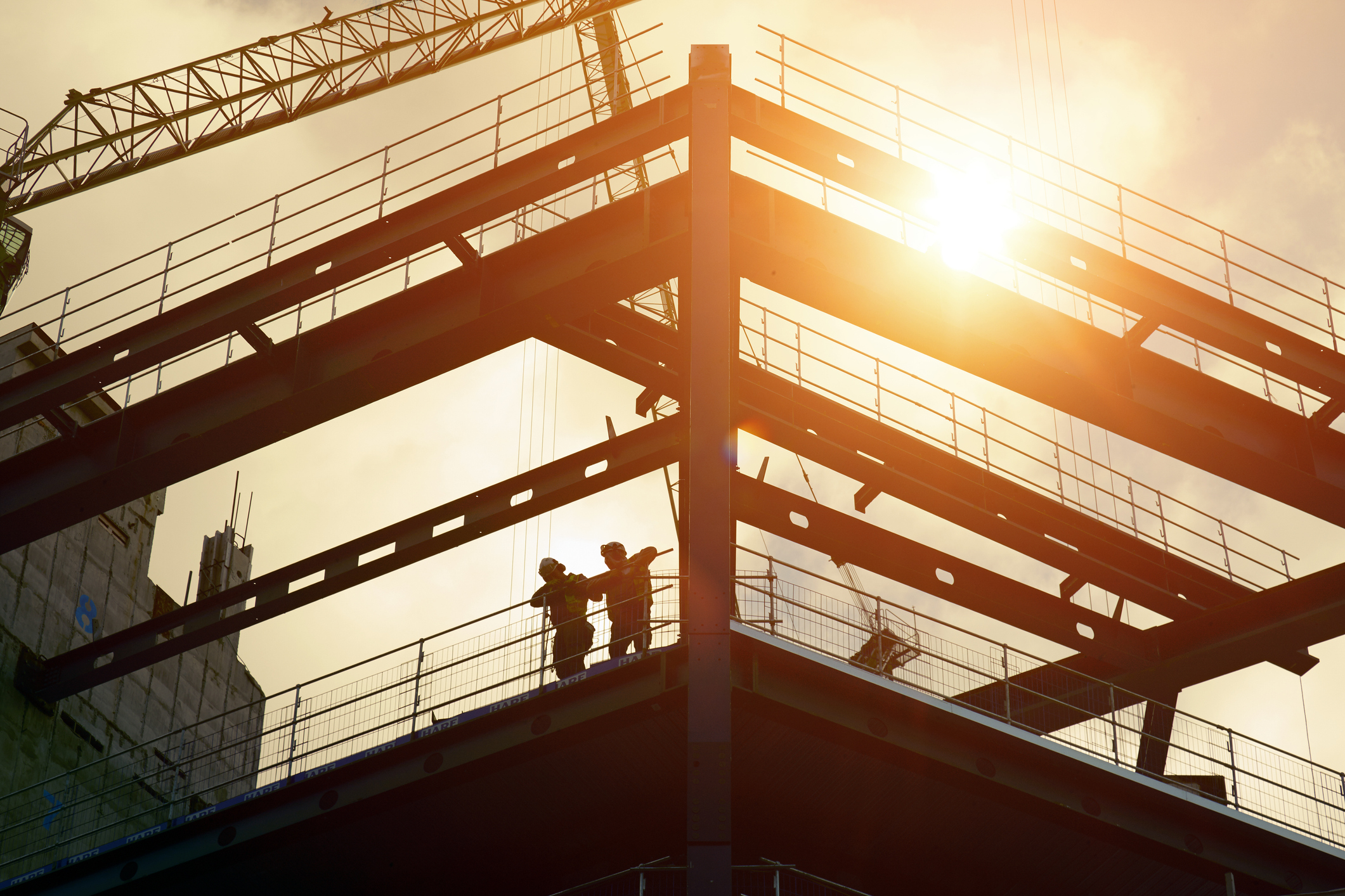 Construction workers silhouetted against the sun
