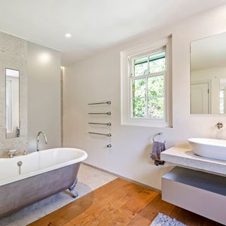 bathroom with wooden flooring and bathtub