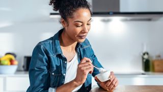 Woman eating yoghurt from a package