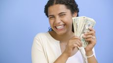 A smiling teenage girl holds quite a lot of cash.